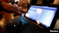 FILE - A man checks the graph showing recent fluctuations on Bitcoin exchange rates against the U.S. dollar on his laptop during a media opportunity at the Tokyo Bitcoin weekly meeting at a restaurant in Tokyo.