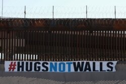 A "#HUGS NOT WALLS" banner is displayed along the border wall as part of 8th annual event on the Rio Grande, in Ciudad Juarez, Mexico, June 19, 2021.