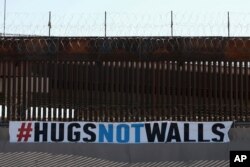 A "#HUGS NOT WALLS" banner is displayed along the border wall as part of 8th annual event on the Rio Grande, in Ciudad Juarez, Mexico, June 19, 2021.