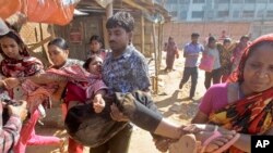 Para pekerja gamen Bangladesh membantu rekannya yang luka saat terjadi bentrokan dengan polisi di Ashulia, luar Dhaka, Bangladesh (12/11).