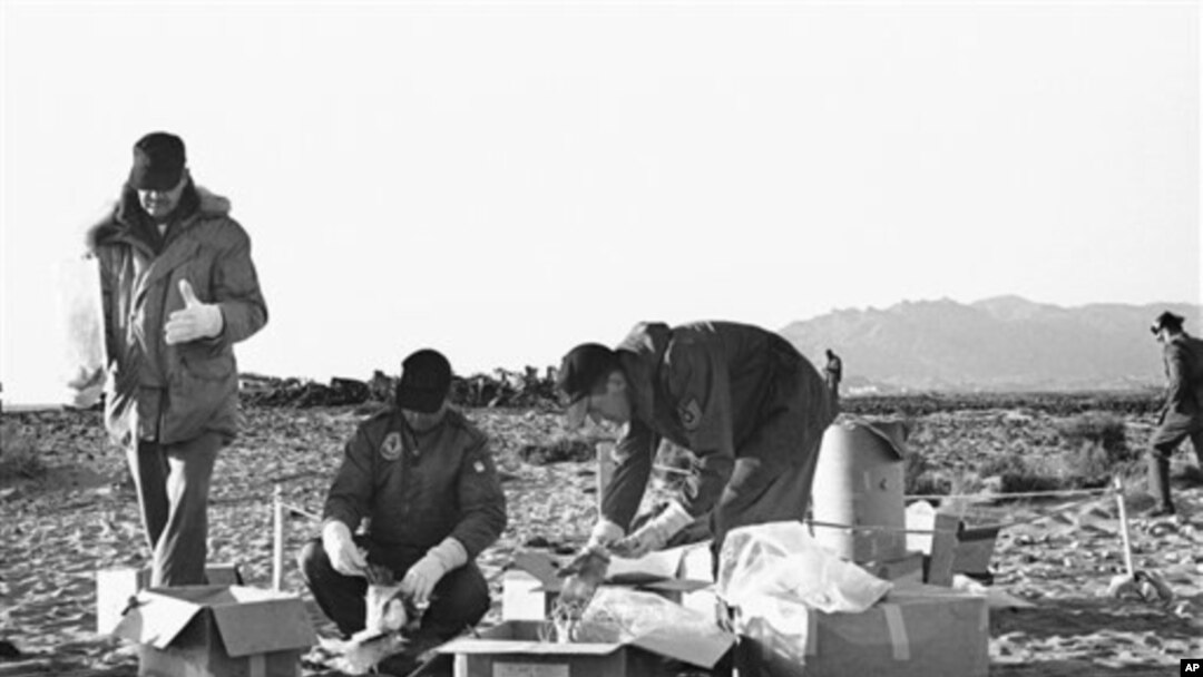 FILE - Technicians of the U.S. Air Force use rubber gloves while picking up pieces of the wreckage and placing them in cardboard boxes in Palomares, Spain, Jan. 28, 1966. 