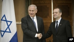 Israeli Prime Minister Benjamin Netanyahu, left, shakes hands with his Romanian counterpart Emil Boc, right, at Victoria Palace in Bucharest, Romania, July 6, 2011