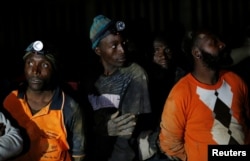 Miners look on after they retrieved the bodies of two other miners from Johannesburg's oldest gold mine in Langlaagte, South Africa, Sept. 13, 2016.