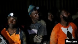 Miners look on after they retrieved the bodies of two other miners from Johannesburg's oldest gold mine in Langlaagte, South Africa, Sept. 13, 2016.