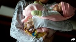 In this May 14, 2015 file photo, a 13-year-old girl holds her one-month-old baby at a shelter for troubled children in Ciudad del Este, Paraguay. The girl said she was raped by her stepfather from the time she was 10 and became pregnant when she was 12. Another pregnant girl, age 11, whose case drew international scorn when Paraguay's government denied her an abortion, gave birth on Thursday, Aug. 13, 2015. The girl was allegedly raped and impregnated by her stepfather when she was 10. In Paraguay, abortion is banned except when the mother's life is in danger. (AP Photo/Jorge Saenz, File)