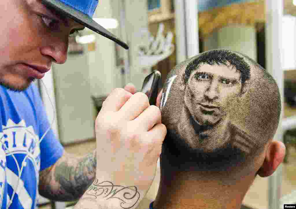 Nghệ sĩ và cũng là chủ tiệm cắt tóc Rob Ferrel (trái) cắt tóc cho khách hàng theo hình chân dung cầu thủ bóng đá người Argentina Lionel Messi ở thành phố San Antonio, bang Texas, Mỹ, ngày 30 tháng 6, 2014.