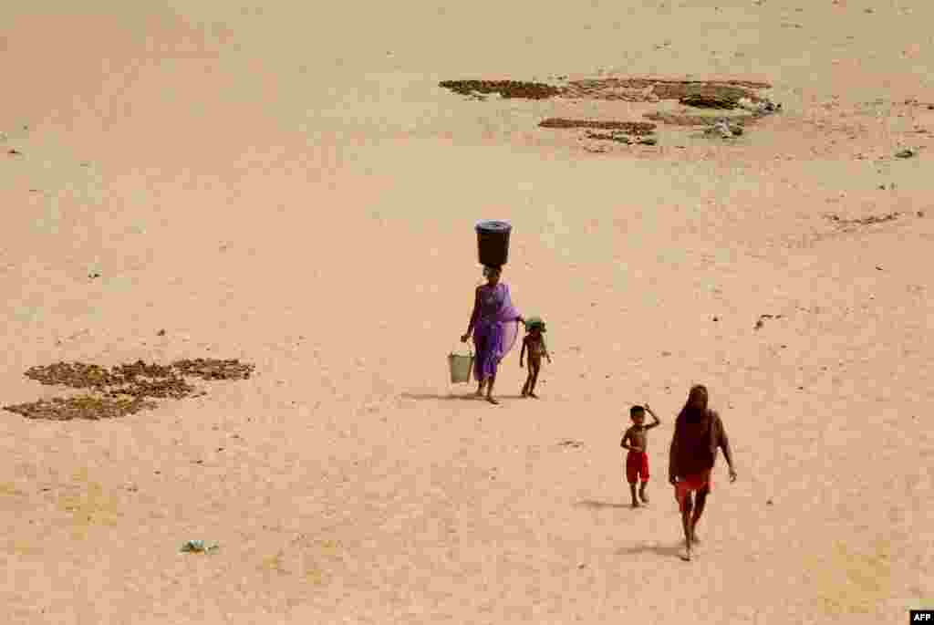 An Indian woman carries a container of drinking water on her head and hold her child’s hand as they walk on the hot sand of the Daya River in the heat on the outskirts of eastern Bhubaneswar. Many of the Indian cities faces severe water scarcity especially in the summer season as summer temperatures soar above the 40°C (104°F).