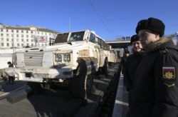FILE - People attend a mobile exhibition installed on freight cars of a train and displaying military equipment, vehicles and weapons, in Sevastopol, Crimea.