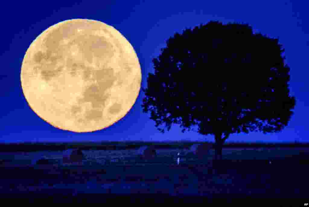 The full moon sets behind the hills of the Taunus region near Wehrheim, Germany.