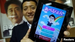 Takuya Hirai, direktur divisi media Internet dari partai berkuasa di Jepang, Partai Demokratis Liberal berpose dengan iPad yang memperlihatkan 'Abe Pyon,' program aplikasi resmi keluaran partai (27/6). (Reuters)