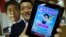 Takuya Hirai, Director of Internet Media Division of Japan's ruling Liberal Democratic Party, poses with an iPad displaying 'Abe Pyon,' LDP's official game application program featuring Shinzo Abe, Japan's prime minister and LDP's leader, at the LDP headq