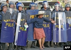 Seorang perempuan berdiri di depan polisi saat buruh Filipina bentrok dengan polisi di wilayah Makati, Manila, pada 16 November 2015. (Foto: Ilustrasi/AFP)