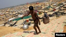 FILE - A Rohingya refugee boy carries water in the Kutupalong refugee camp, in Cox's Bazar, Bangladesh, March 22, 2018. 