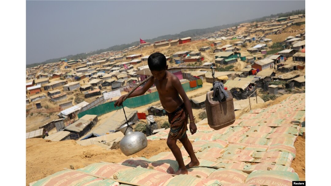 FILE - A Rohingya refugee boy carries water in the Kutupalong refugee camp, in Cox's Bazar, Bangladesh, March 22, 2018.