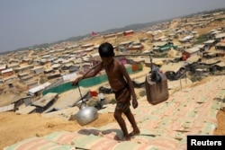 FILE - A Rohingya refugee boy carries water in the Kutupalong refugee camp, in Cox's Bazar, Bangladesh, March 22, 2018.