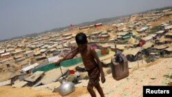 FILE - A Rohingya refugee boy carries water in the Kutupalong refugee camp, in Cox's Bazar, Bangladesh, March 22, 2018.