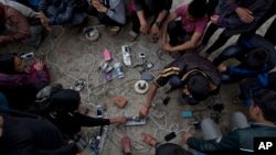 Warga desa Nepal mengisi baterai ponsel mereka di tempat terbuka di Kathmandu (27/4). (AP/Bernat Armangue)