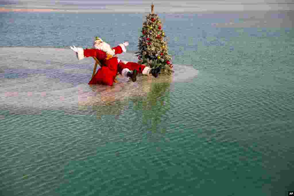Issa Kassissieh dressed as Santa Claus sits next to a Christmas tree on a salt formation during filming for a Christmas greeting video from the Holy Land in the Dead Sea near Ein Bokeq, Israel.