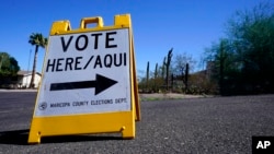 ARCHIVO - Un cartel marca la entrada a un distrito electoral en el primer día de votación anticipada para las elecciones generales en Phoenix, el 12 de octubre de 2022.