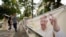 People walk past in front of a poster with a photo of Pope Francis ahead of his visit to Singapore on the street in Singapore, Sept. 10, 2024.