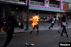 A man who was set on fire by people accusing him of stealing during a rally against President Nicolas Maduro runs amidst opposition supporters in Caracas, Venezuela, May 20, 2017.
