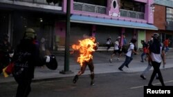 A man who was set on fire by people accusing him of stealing during a rally against President Nicolas Maduro runs amidst opposition supporters in Caracas, Venezuela, May 20, 2017. 