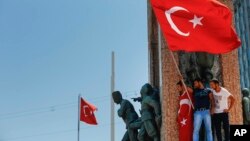 Des manifestants opposés au coup d'Etat agitent un drapeau turc au-dessus d’un monument sur la place Taksim, Istanbul, Turquie, 16 juillet 2016. (AP Photo / Emrah Gurel)