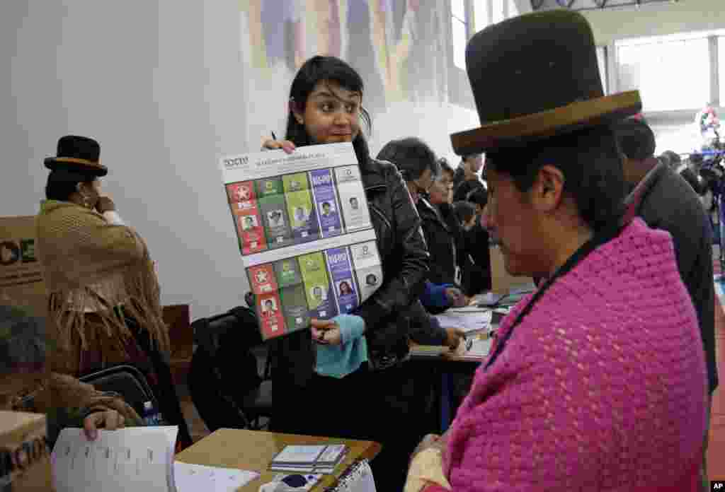 An elections delegate shows an unmarked ballot before giving it to a voter at the polling station in La Paz, Oct. 12, 2014. 