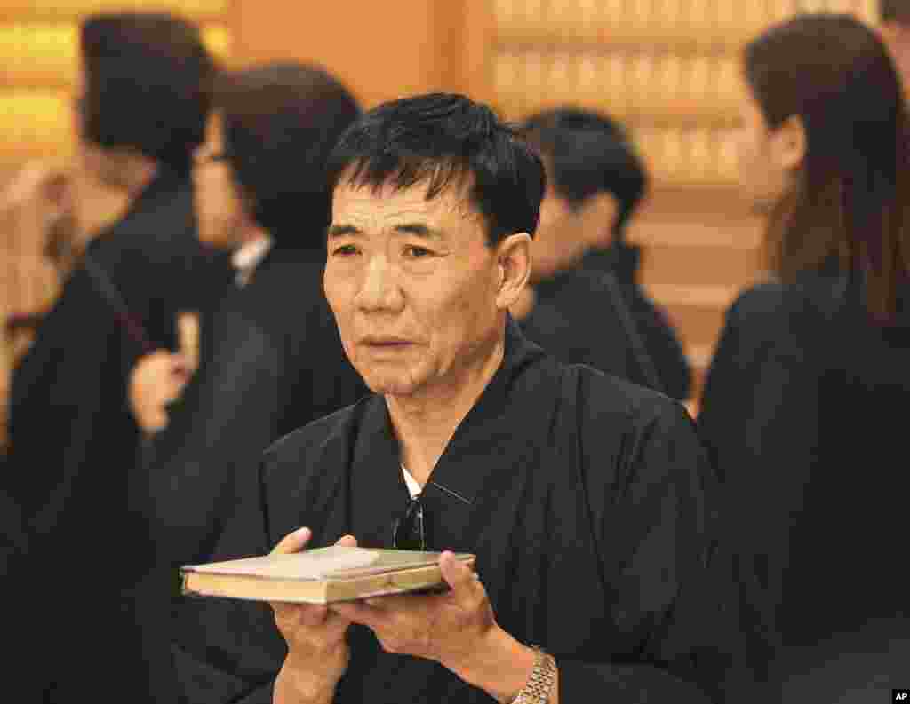 A Chinese relative of passengers on board Flight MH370 carries a book as he attends prayers at a Buddhist temple in Petaling Jaya, Malaysia, March 31, 2014.