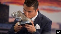 Real Madrid’s striker Cristiano Ronaldo kisses a silver boot award for scoring the most goals for the club during a ceremony at the Santiago Bernabeu stadium in Madrid, Spain, Oct. 2, 2015.