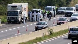 Police stand near a truck stopped on the side of the highway near Parndorf south of Vienna, Austria, Aug 27, 2015. Officials say up to 50 migrants were found dead in the truck. They reportedly suffocated.