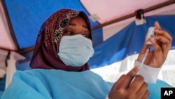 FILE - A nurse prepares to administer an AstraZeneca vaccination against COVID-19, at a district health center giving first, second, and booster doses to eligible people, in the low-income Kibera neighborhood of Nairobi, Kenya, Jan. 20, 2022.