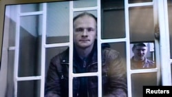 Photographer Denis Sinyakov, one of 30 people detained after a Greenpeace protest at Prirazlomnaya platform, is seen on a screen inside a court building during a court session in Murmansk, Russia, Oct. 8, 2013.