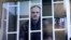 Photographer Denis Sinyakov, one of 30 people detained after a Greenpeace protest at Prirazlomnaya platform, is seen on a screen inside a court building during a court session in Murmansk, Russia, Oct. 8, 2013.