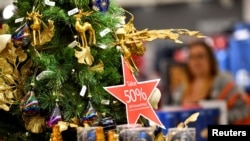 FILE - A star-shaped placard hanging from a Christmas tree states "Take 50% Off Ticketed Price" at a Macy's store at the King of Prussia Mall in King of Prussia, Pennsylvania, Nov. 22, 2019.