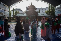 Umat Muslim membawa barang-barang yang disumbangkan oleh konsulat China di Masjid Cheng Ho di Surabaya pada 6 Mei 2021, menjelang Idul Fitri yang menandai berakhirnya bulan suci Ramadhan. (Foto: AFP/Juni Kriswanto)