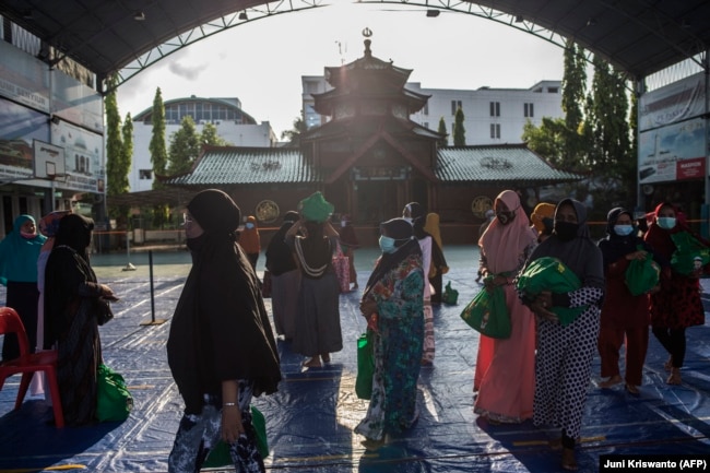 Umat Muslim membawa barang-barang yang disumbangkan oleh konsulat China di Masjid Cheng Ho di Surabaya pada 6 Mei 2021, menjelang Idul Fitri yang menandai berakhirnya bulan suci Ramadhan. (Foto: AFP/Juni Kriswanto)