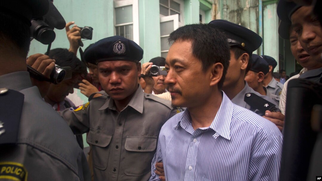 FILE - Kyaw Min Swe, center, is escorted by police upon arrival at the township court in Yangon, Myanmar, June 16, 2017. The journalist was arrested at his home in Yangon on April 11, 2023, after posting a black square on Facebook, in an apparent comment related to an airstrike.