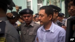 FILE - Kyaw Min Swe, center, is escorted by police upon arrival at the township court in Yangon, Myanmar, June 16, 2017. The journalist was arrested at his home in Yangon on April 11, 2023, after posting a black square on Facebook, in an apparent comment related to an airstrike.