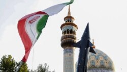 Iranians lift up a flag and the mock-up of a missile during a celebration following Iran's missiles and drones attack on Israel, on April 15 2024, at Palestine square in central Tehran.