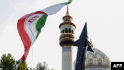 Los iraníes levantan una bandera y la maqueta de un misil durante una celebración tras el ataque con misiles y drones de Irán contra Israel, el 15 de abril de 2024, en la plaza Palestina en el centro de Teherán.
