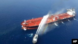 An Iranian navy boat sprays water to extinguish a fire on an oil tanker in the sea of Oman, June 13, 2019.