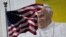 FILE - The U.S. flag flies in front of a mural of Pope Francis on the side of a building in midtown Manhattan in New York, Aug. 28, 2015.