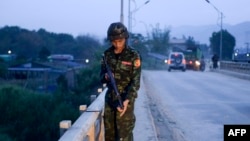 Foto yang diambil tanggal 12 Mei 2018 menunjukkan seorang anggota kelompok bersenjata dukungan tentara mengamankan sebuah jembatan di Muse, Myanmar (foto: AFP Photo)