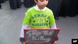 In this citizen journalism image made on a mobile phone, a Syrian boy carries a board that reads:" stop the killing," during a protest in Daraya, southwest of Damascus, Syria, April 25, 2011