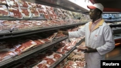 FILE: A shop worker arranges packaged meat at a leading supermarket in Harare January 16, 2012. Zimbabwe's headline consumer inflation rate quickened to 4.9 percent year-on-year in December, higher than government's year-end target for 2011.