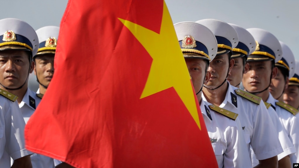 FILE - Vietnam People's Navy personnel carry their country's national flag.