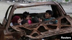 Niños juegan en un carro destrozado en la ciudad de n Aleppo, Syria, Feb. 16, 2015. 