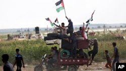 FILE - Men wave national flags while riding a motorcycle loaded with tires to be burned during a protest at the Gaza Strip's border with Israel, Aug. 3, 2018. Gaza's Hamas rulers led several thousand Palestinians in a protest along the frontier with Israel.