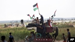 Men wave national flags while riding a motorcycle tax loaded with tires to be burned during a protest at the Gaza Strip's border with Israel, Aug. 3, 2018. Gaza's Hamas rulers led several thousand Palestinians in a protest along the frontier with Israel.